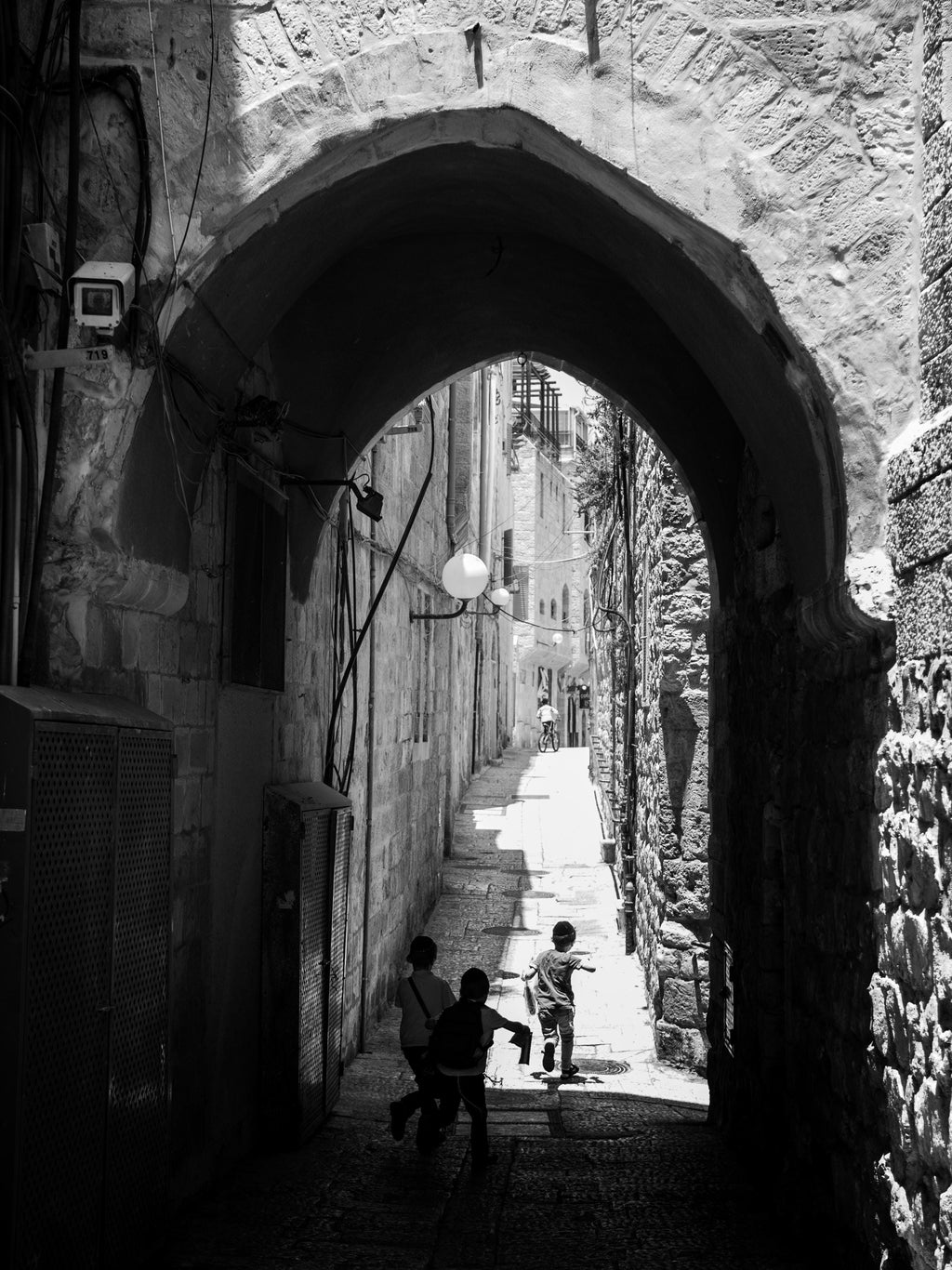 Black and White Jerusalem Old City Pedestrian Street with Jewish Children running from school and Stone Arche