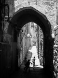 Black and White Jerusalem Old City Pedestrian Street with Jewish Children running from school and Stone Arche